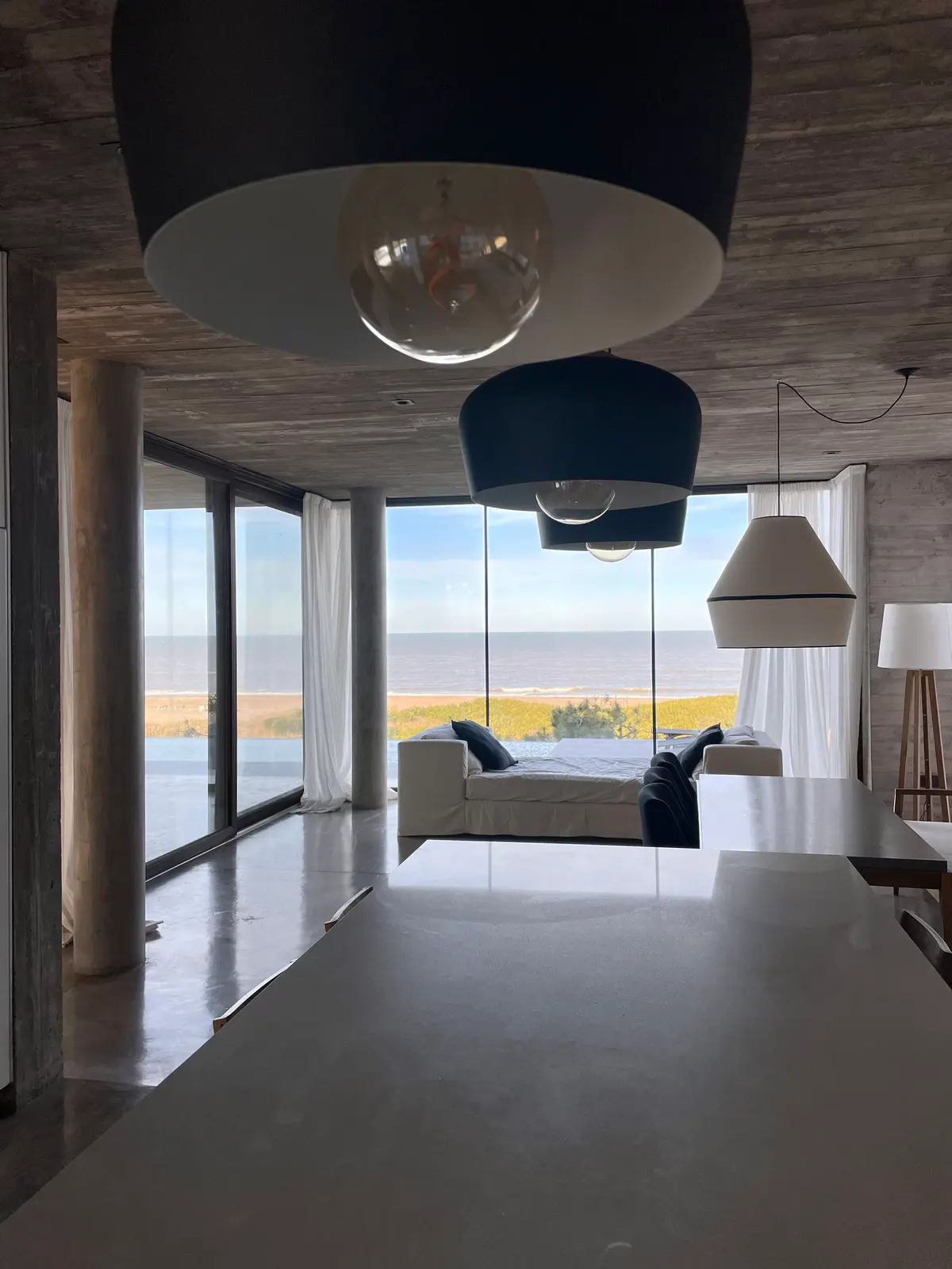 Living moderno con vista al mar y detalles de hormigón — proyecto CASA sobre el MAR, por Guerrero Arquitectos, en Pinamar
