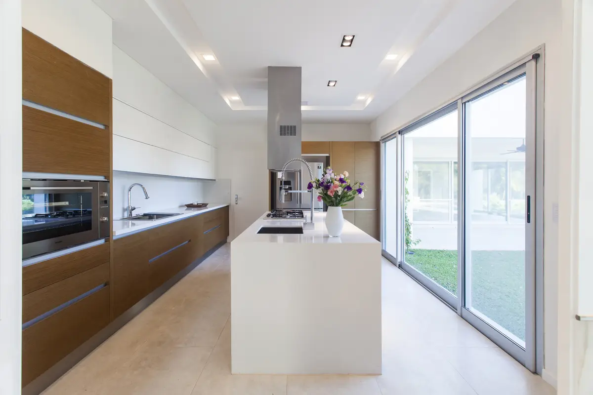 cocina moderna con isla central y mucha luz natural — proyecto Modernismo Náutico, por Apaarquitectura, en Tigre