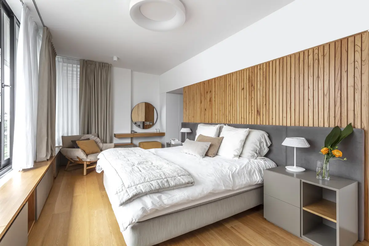 Dormitorio minimalista con pared de madera y luz cálida — proyecto Nordelta, por Judith Babour, en Nordelta