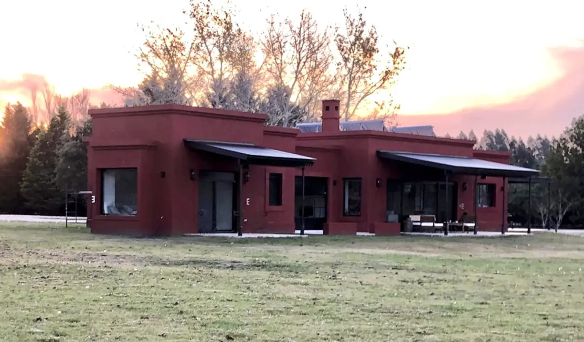 Casa moderna terracota com grandes janelas e galerias ao pôr do sol — projeto Las Vizcachas, por Marconi Silva Arquitectos, em Los Cardales