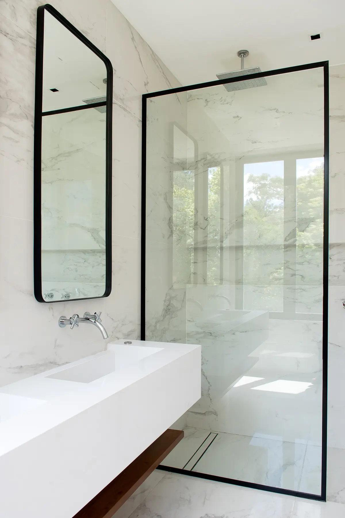 Banheiro moderno com mármore branco, espelho preto e box de vidro — projeto Bosque Chico, por Estudio Arq. María Sioli, em Garin
