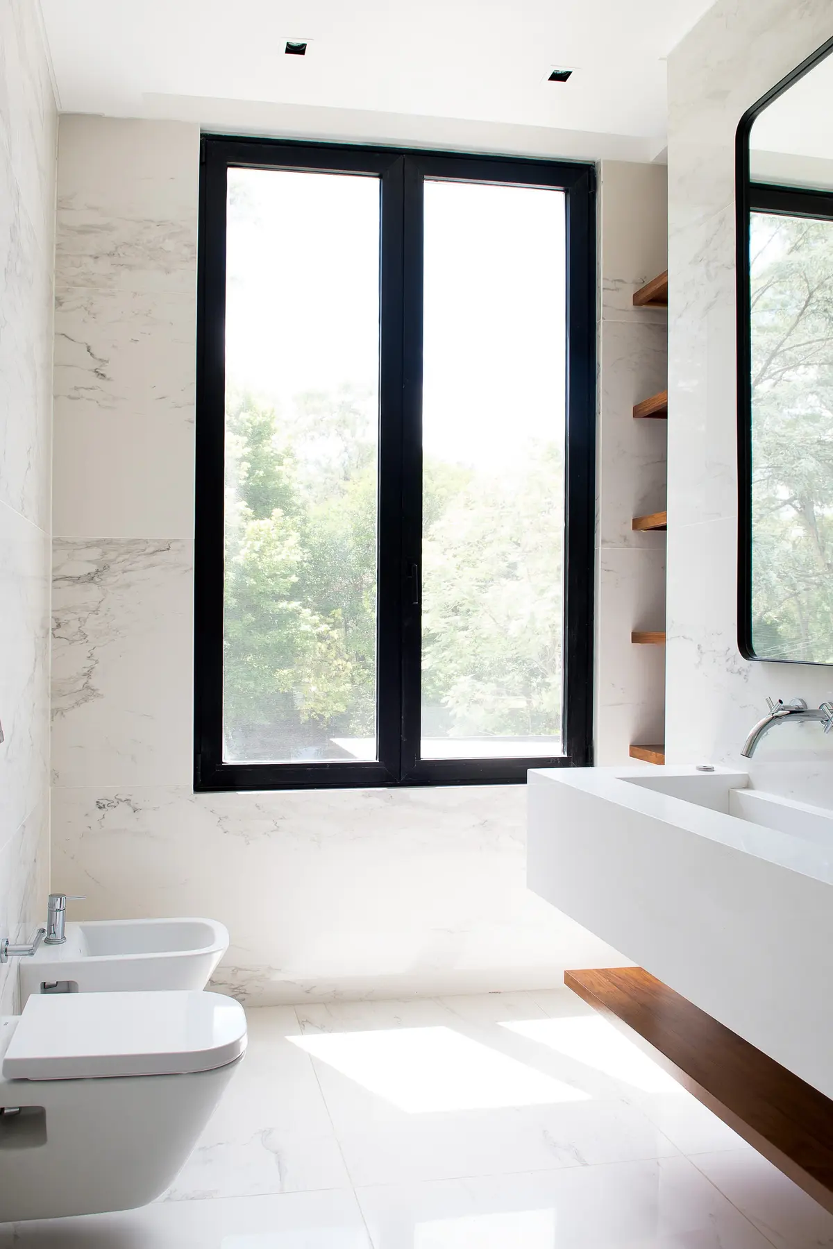 Banheiro moderno minimalista com mármore branco e janelões para a floresta — projeto Bosque Chico, por Estudio Arq. María Sioli, em Garin