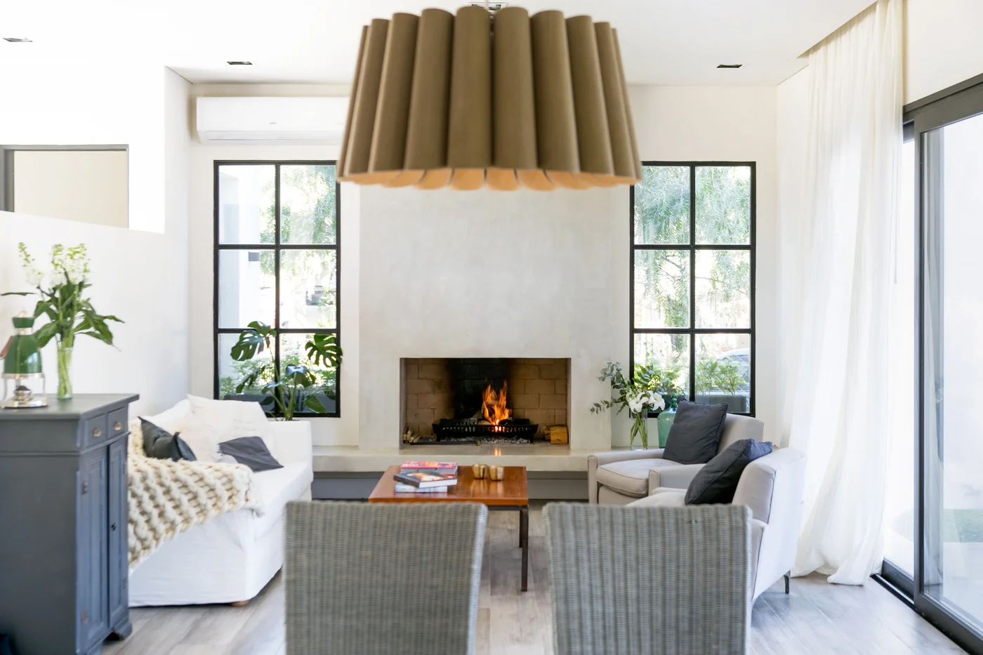 Living comedor moderno con chimenea y gran lámpara cónica.