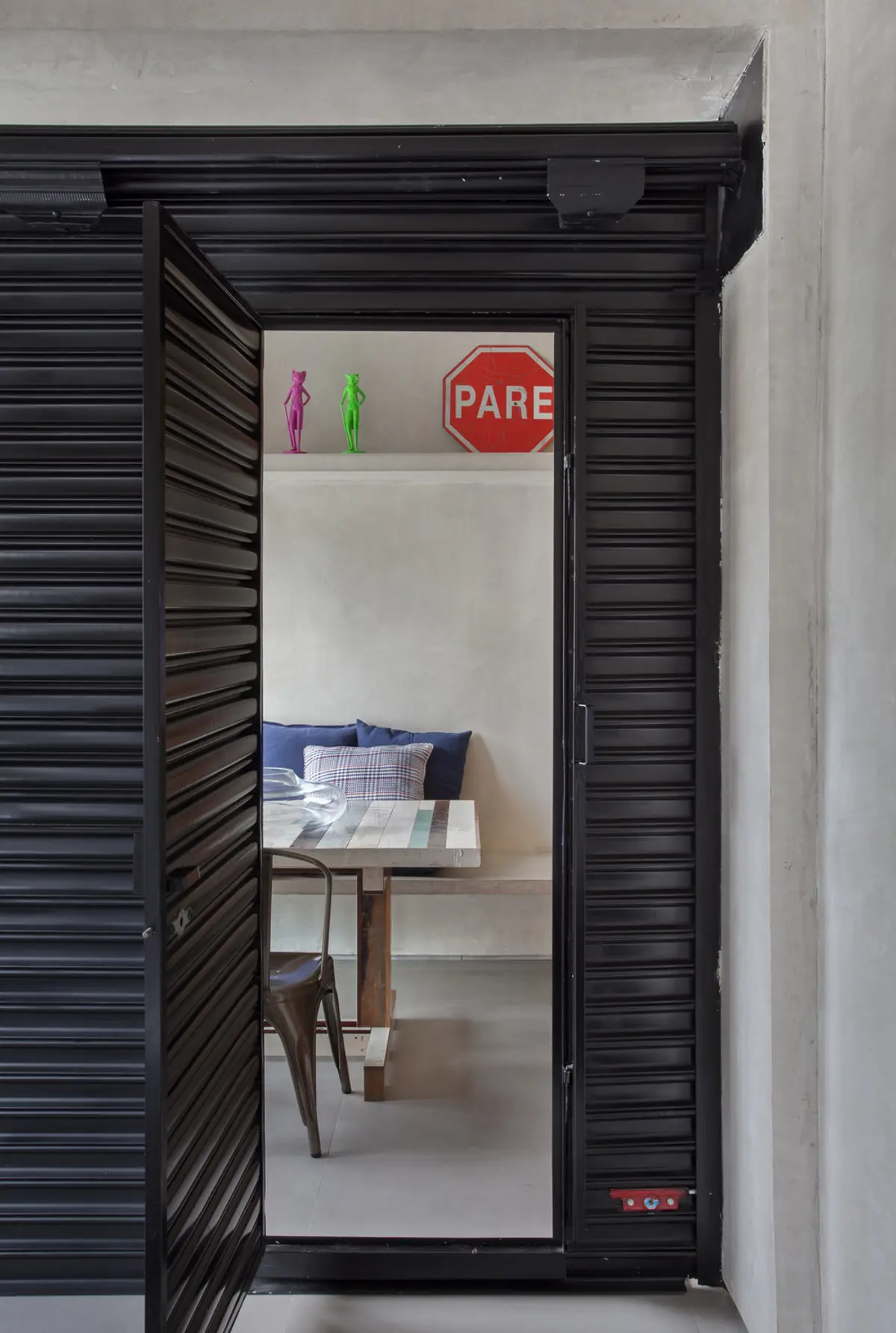 Dormitorio con puerta de madera negra entreabierta, cama y escritorio interior — proyecto MM House, por Studio Ro-ca