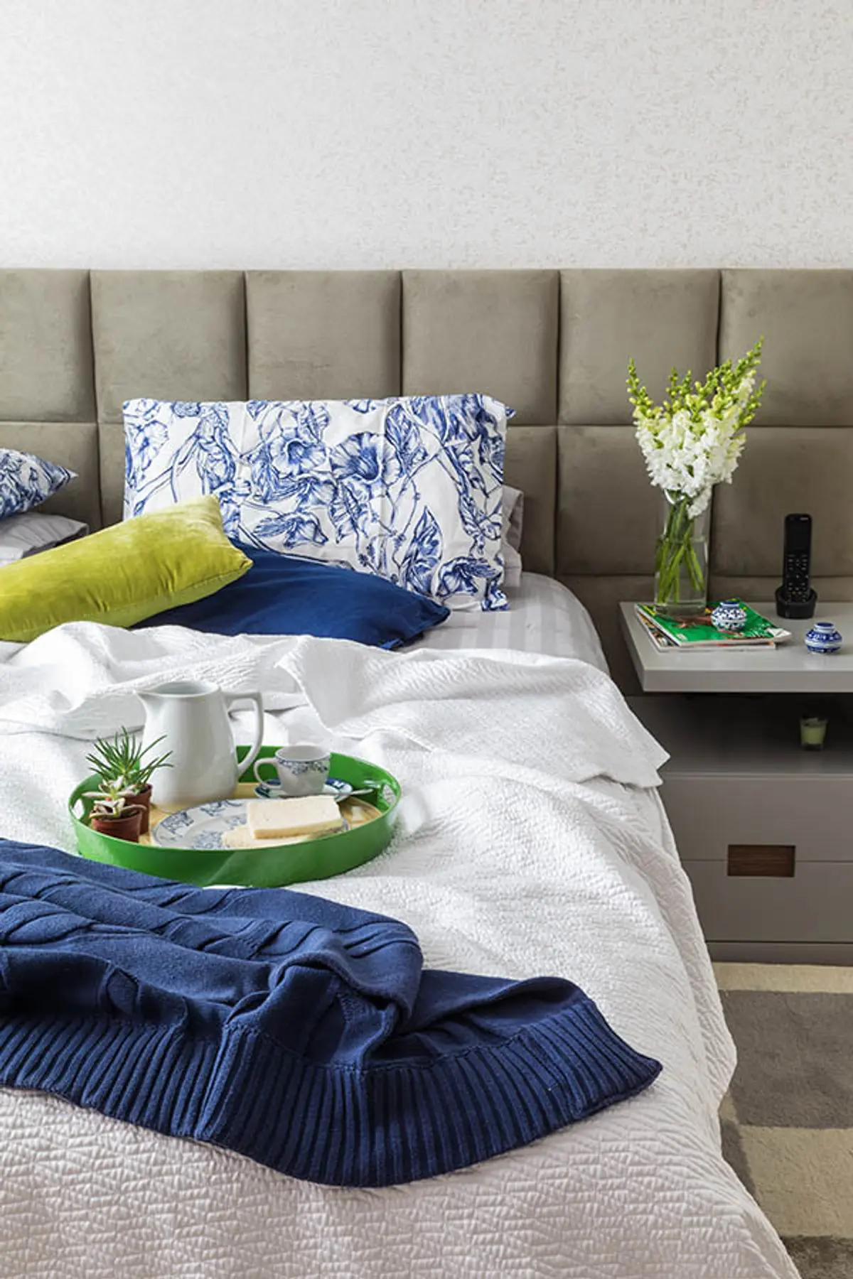 Dormitorio moderno con cabecero tapizado gris, ropa de cama azul y blanca — proyecto Casa Barra ED, por Amanda Miranda