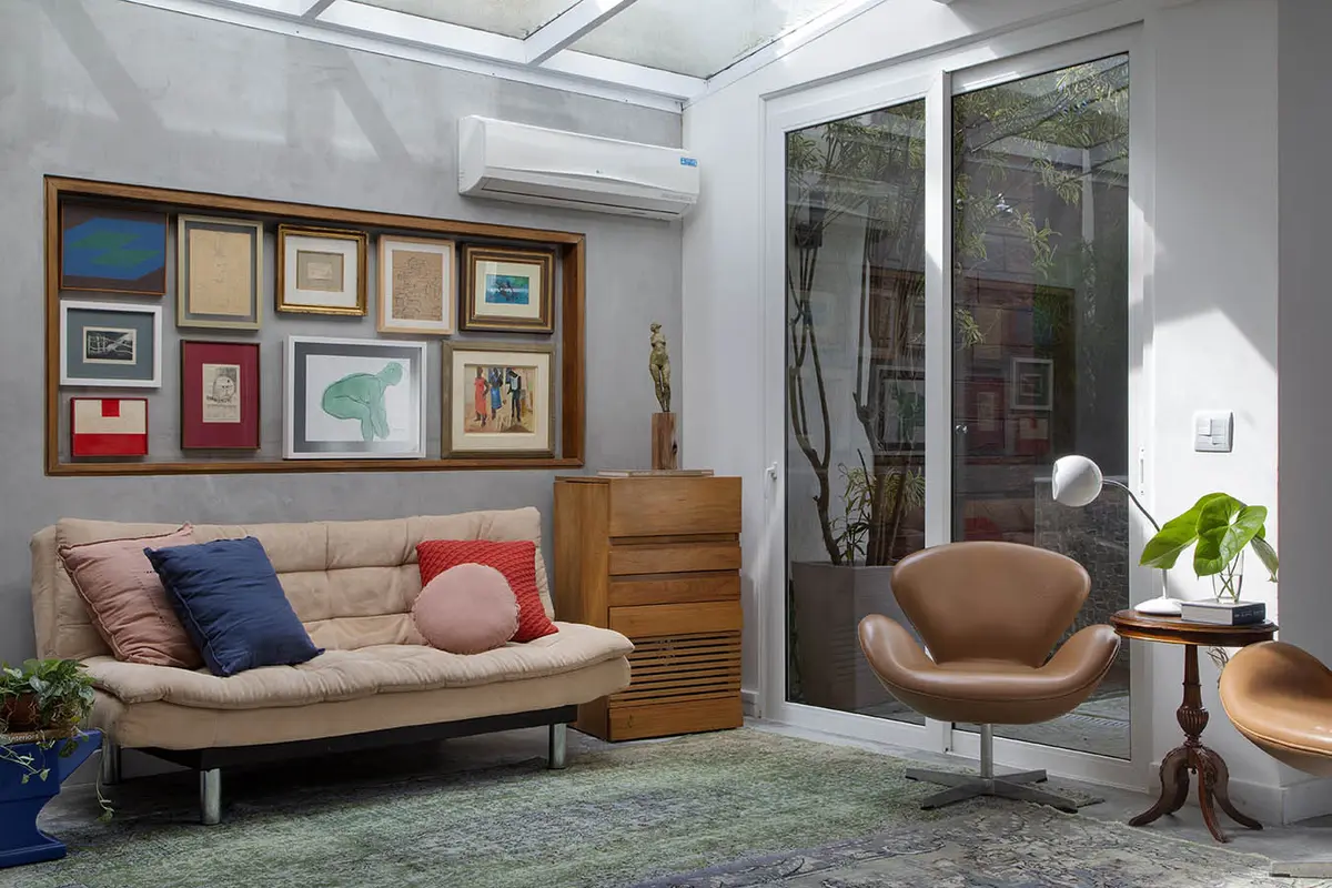 Living moderno con sofa beige, sillon cuero y galeria de arte — proyecto Casa Jardim Guanabara, por Amanda Miranda