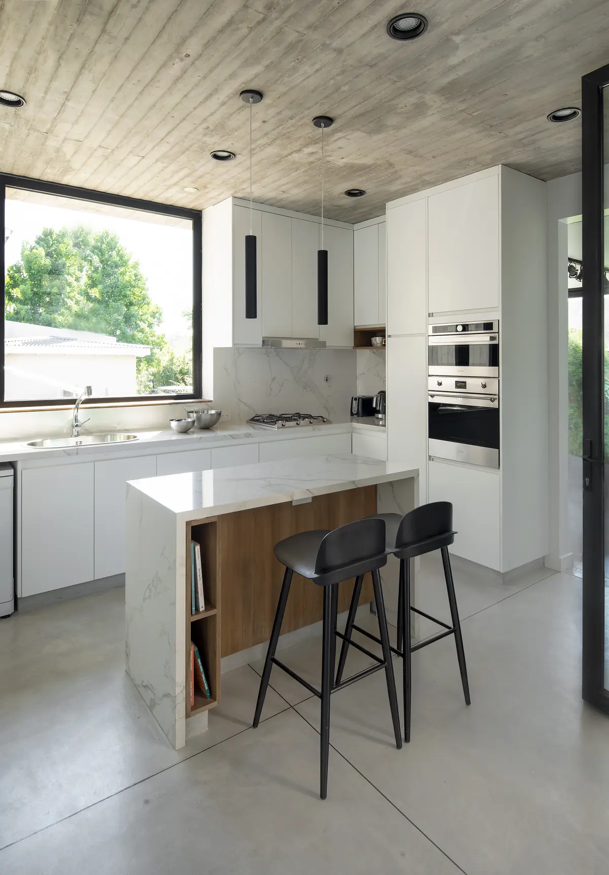 Cozinha moderna com ilha de mármore, teto de concreto e janelas amplas — projeto Casa PVTM, por Estudio Lak, em Barrio Laguna del Sol