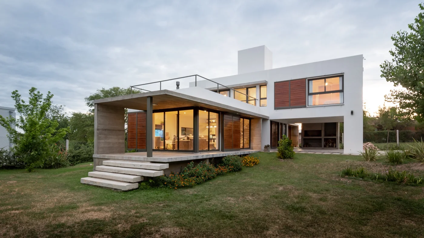 Casa contemporánea con fachada mixta, ventanales amplios y pérgola.