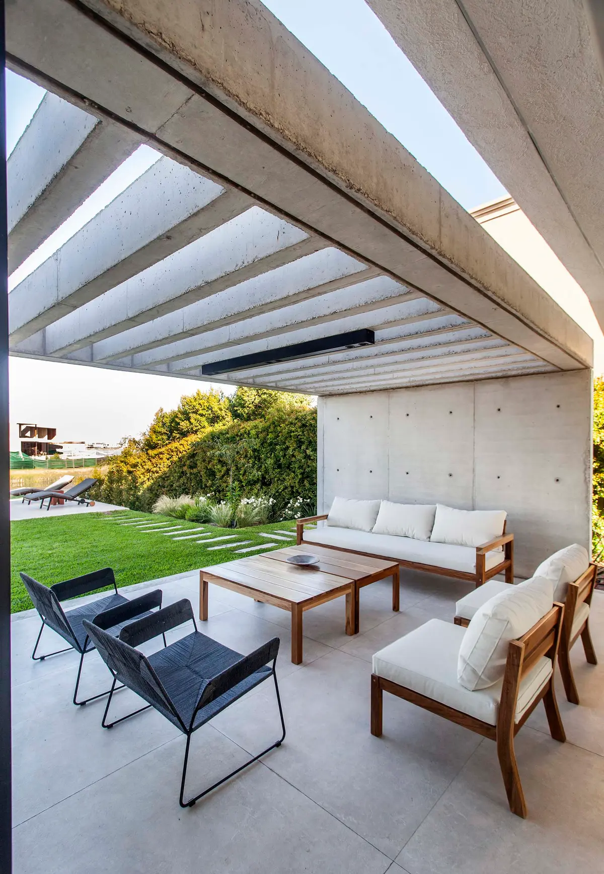 Pátio moderno com pergolado de concreto e móveis brancos — projeto CASA J2M, por GMARQ, em Belén de Escobar