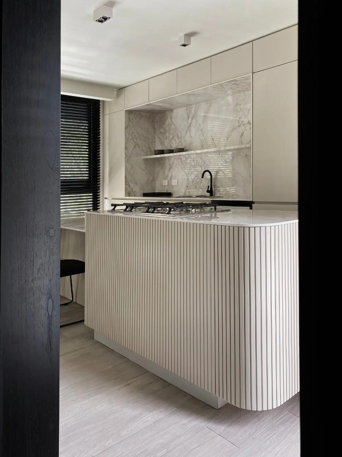 Cocina moderna con isla curva de listones y mármol en la pared — proyecto Pampa, por ABEJA CONCEPT, en Belgrano