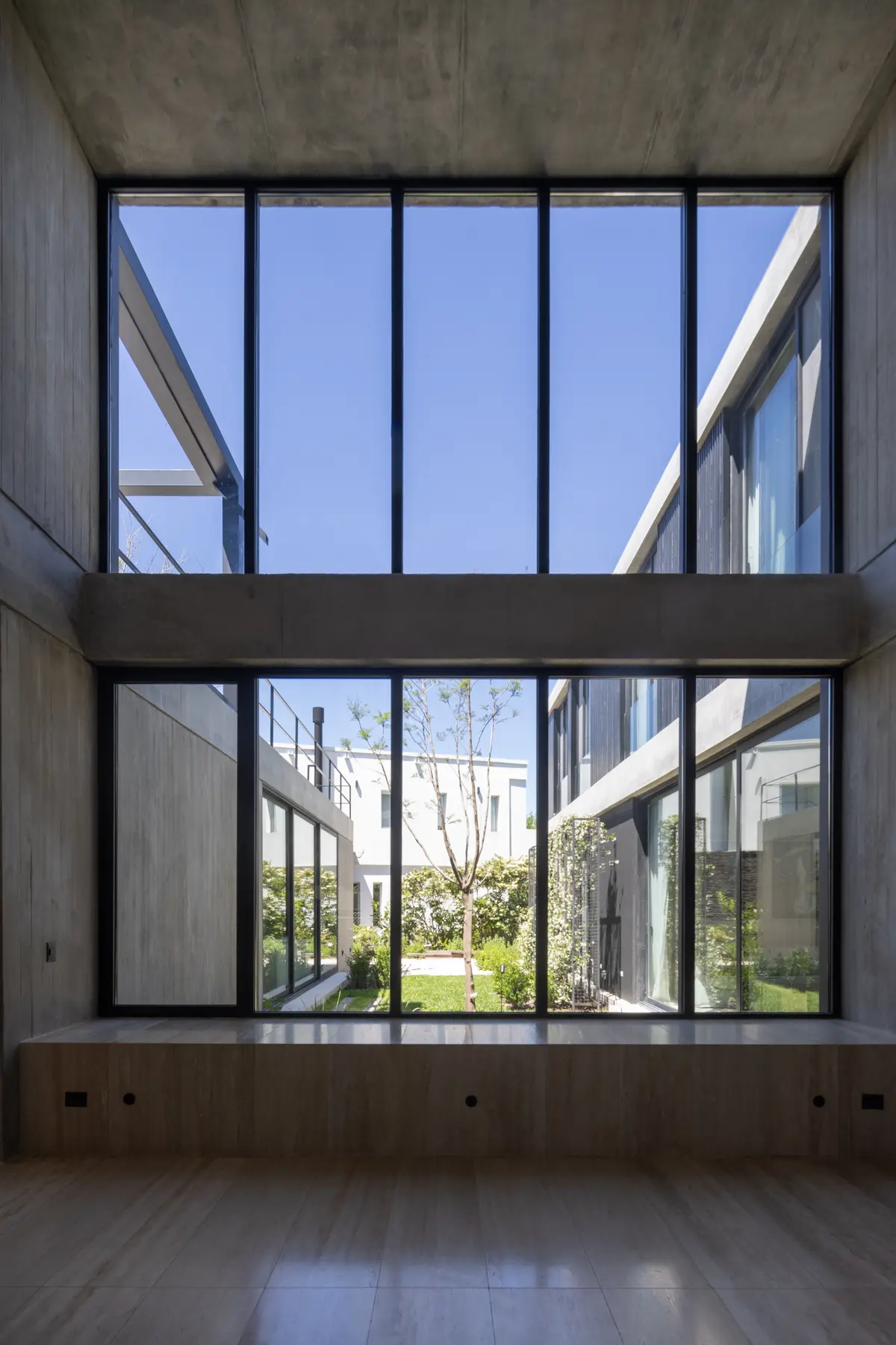 Sala moderna com concreto aparente e enormes janelas para um pátio — projeto CASA AWA, por radovic_arquitecto, em Benavidez