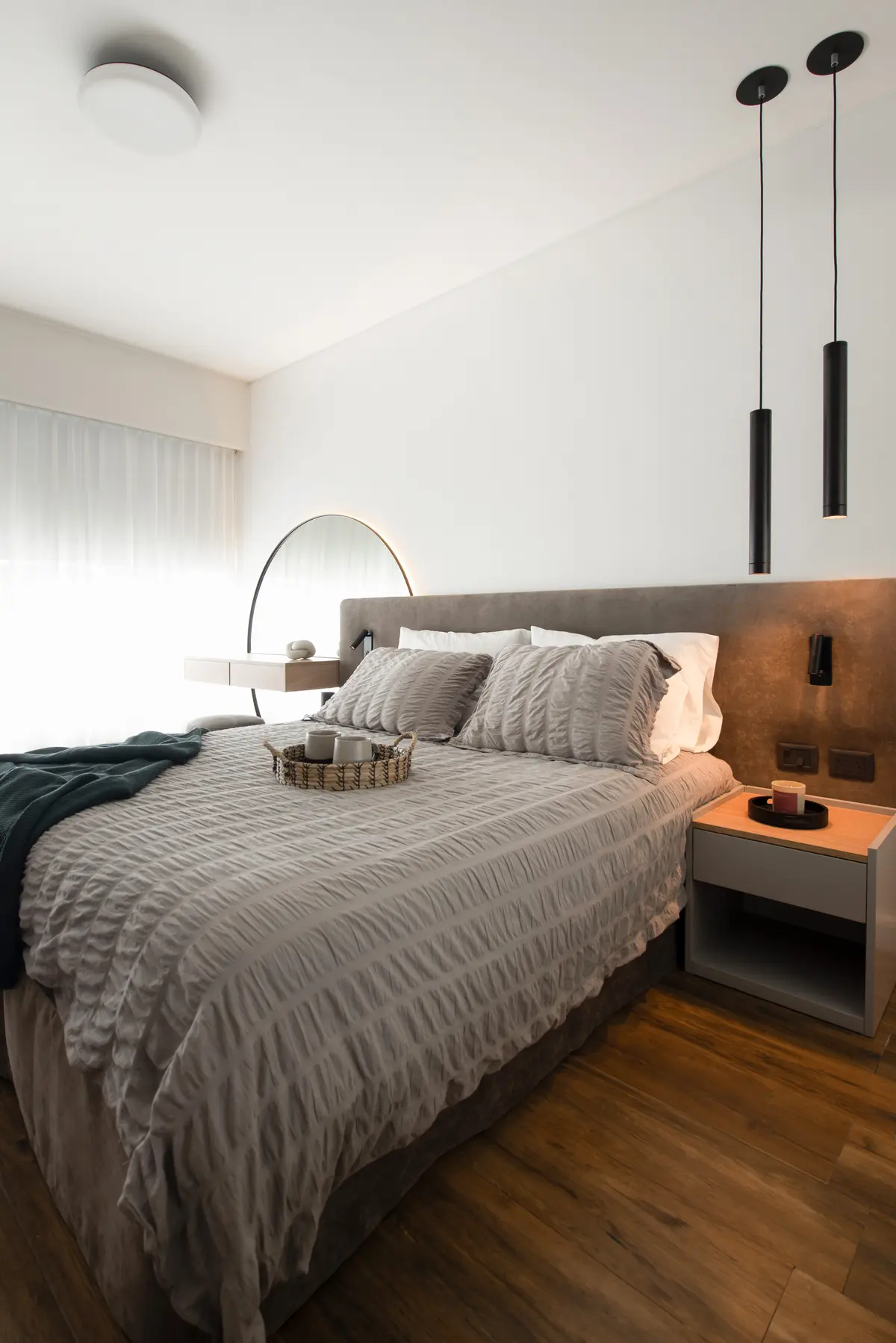 Dormitorio moderno con cama grande, luces colgantes cilíndricas y suelo de madera oscura — proyecto Artilleros Plaza, por C - ESTUDIO, en Buenos Aires