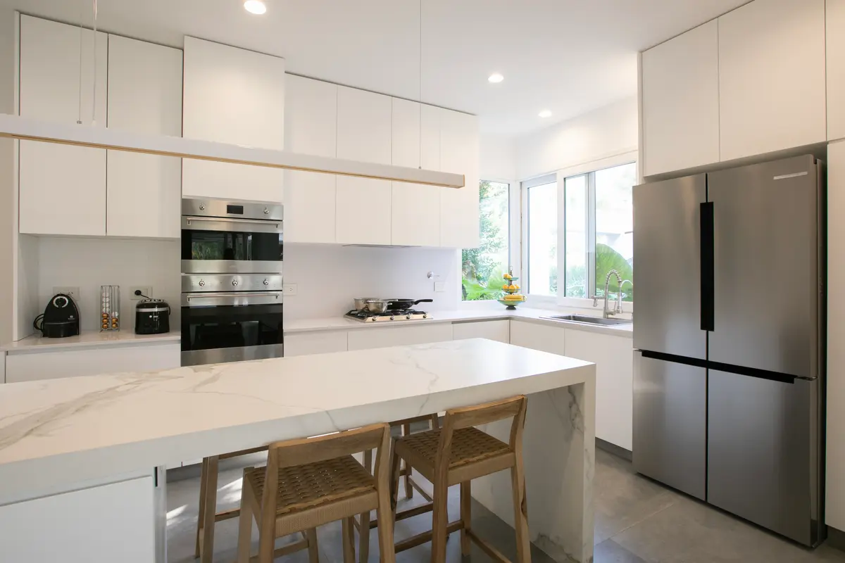 Cozinha moderna com ilha de mármore e eletrodomésticos embutidos — projeto Obra Newman FH, por Arq. Lourdes Yarade Saravia, em Benavidez