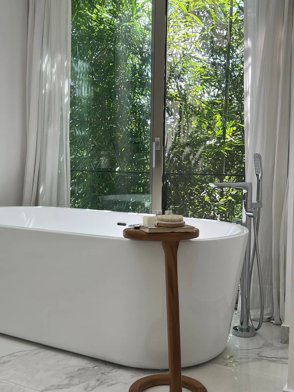 Baño moderno con bañera exenta y gran ventana al bosque — proyecto Casa AJ, por Estudio Junor, en Pilar