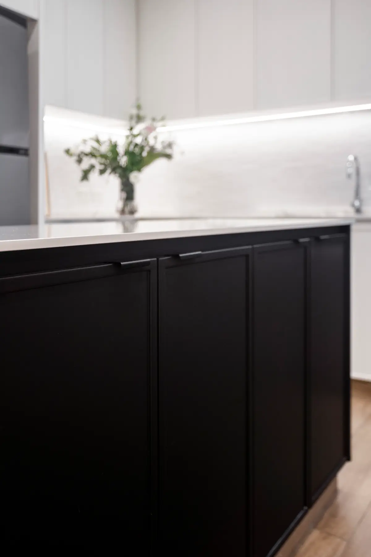 Cocina moderna con isla negra, encimeras de mármol y luz indirecta — proyecto Bustamante, por JT ARQUITECTURA, en Buenos Aires