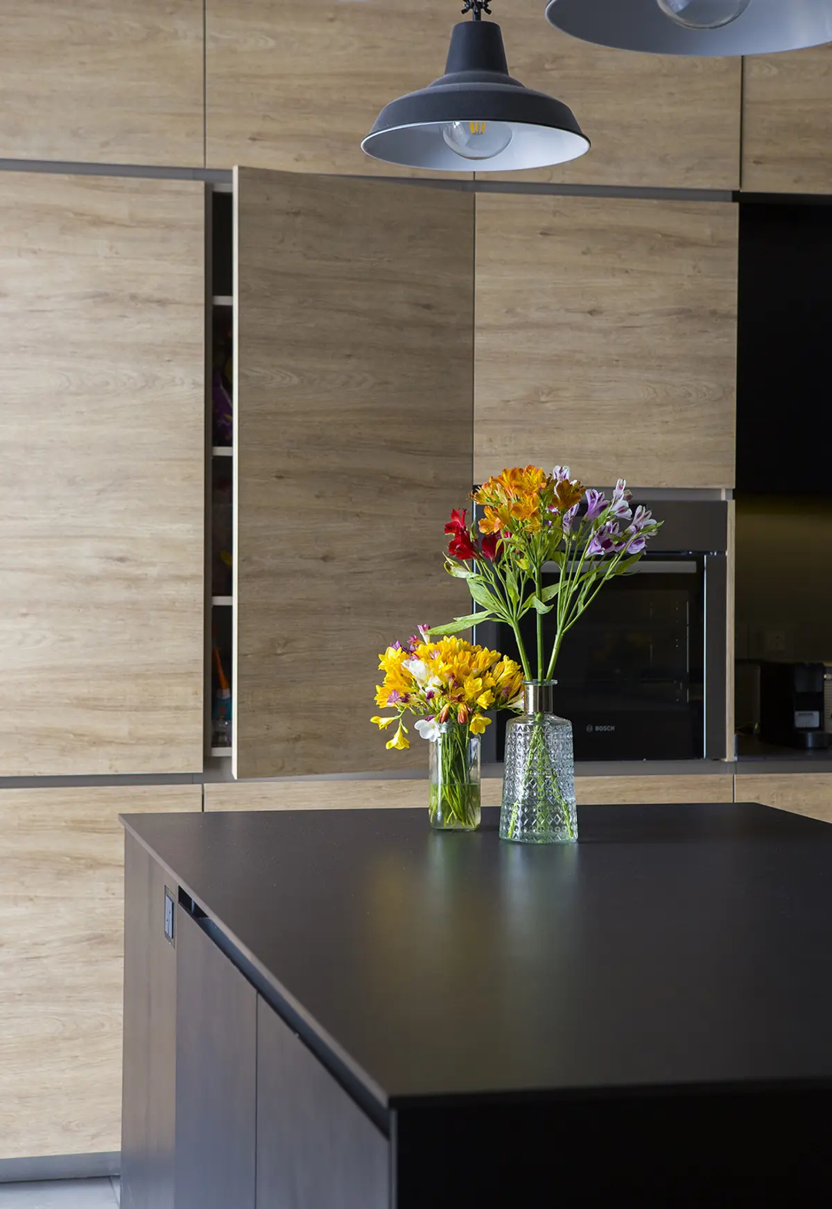 Cocina moderna con isla, luces colgantes industriales y gabinetes de madera — proyecto Obra RVR - Reforma cocina, por LOB arquitectura