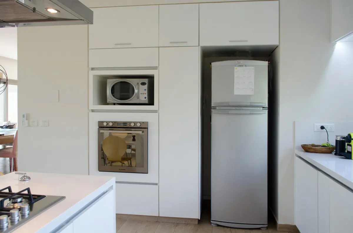 Cocina moderna con gabinetes blancos y electrodomésticos integrados — proyecto Casa Nordelta, por linearecta.arquitectura, en Nordelta