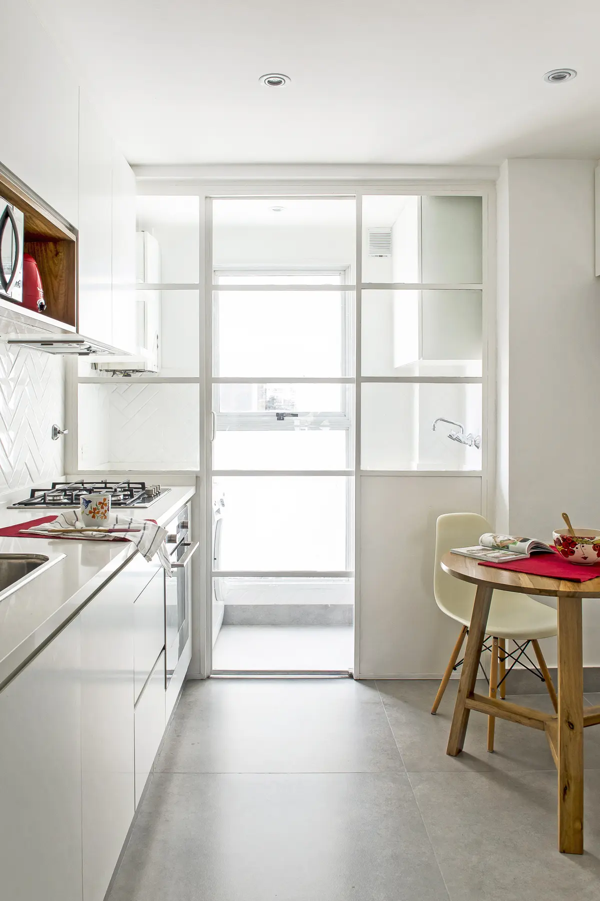 Cocina moderna con azulejos blancos, mesa redonda de madera y mampara de vidrio — proyecto Oro, por Estudio Arq. María Sioli, en CABA