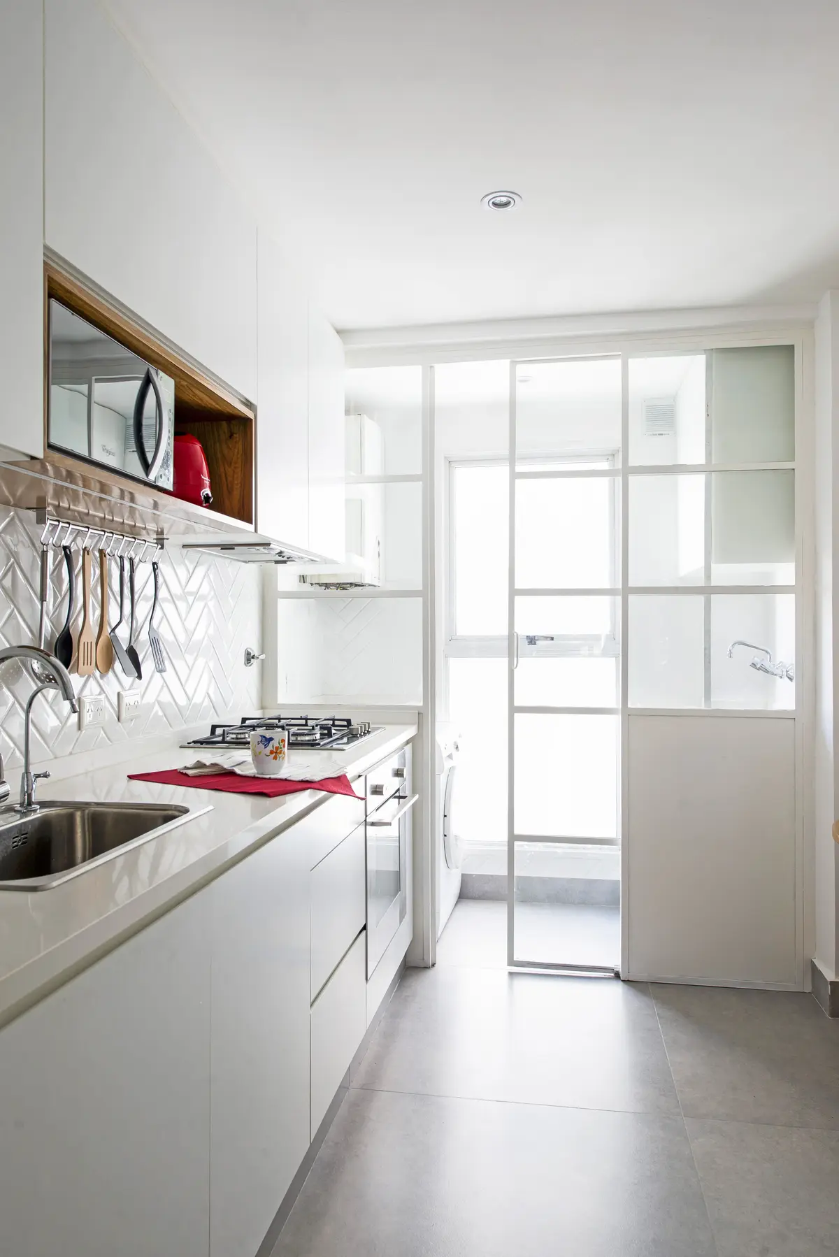 Cocina moderna con azulejos blancos en espiga y partición de vidrio — proyecto Oro, por Estudio Arq. María Sioli, en CABA