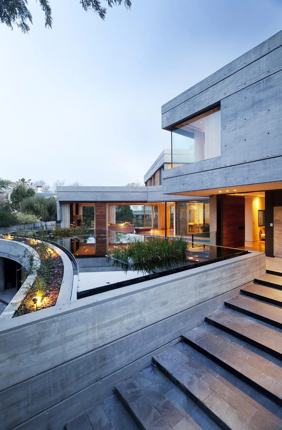 Casa moderna con concreto expuesto y jardín curvo — proyecto Acasusso, por Remy Arquitectos, en Acassuso