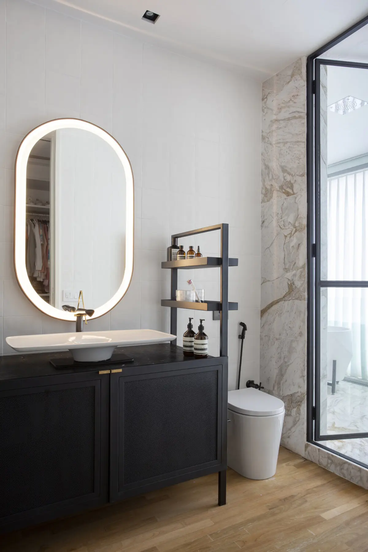 Bano moderno con espejo ovalado iluminado y mueble negro — proyecto BM House, por Studio Ro-ca