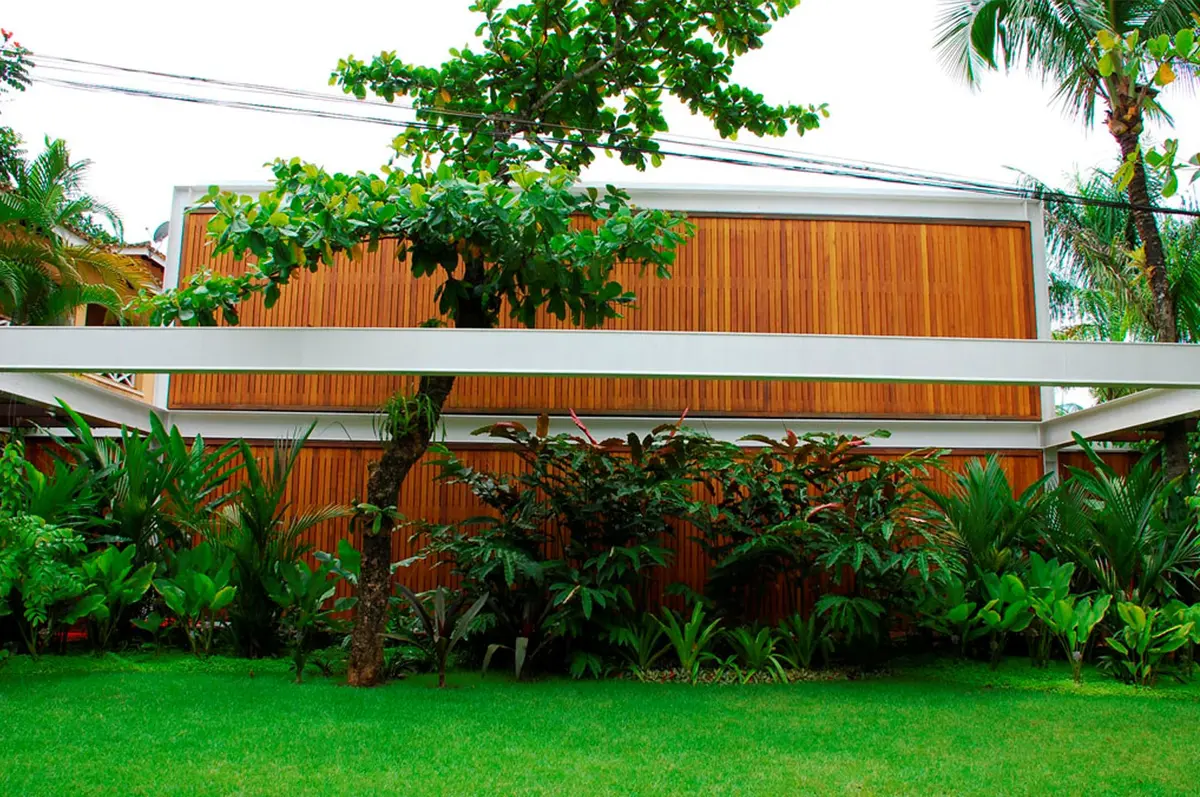 Casa moderna con jardín verde y estructura de madera y hierro — proyecto Residência MI, por Gil Fialho
