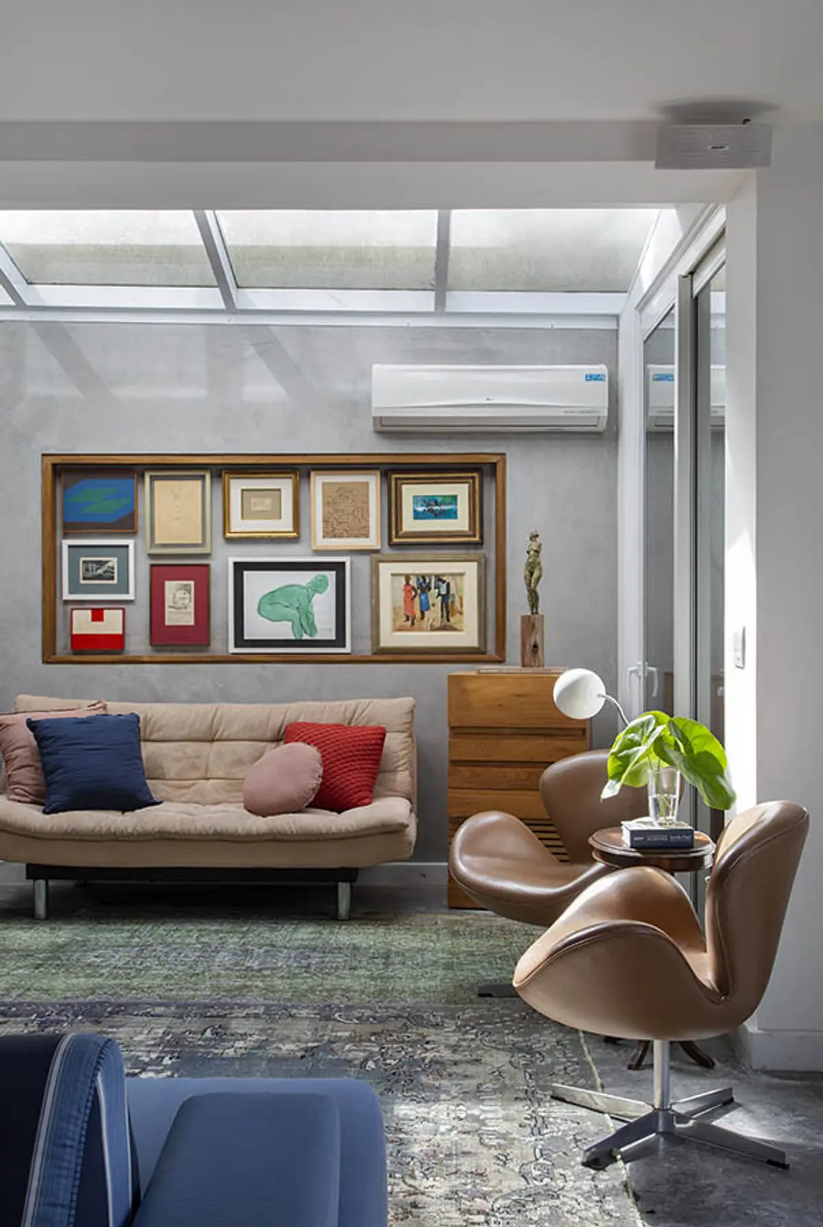 Living con sofá beige, sillones de cuero y galería de arte en pared — proyecto Casa Jardim Guanabara, por Amanda Miranda