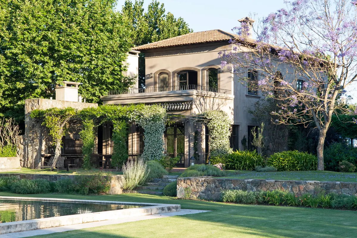 Villa mediterranea con pileta frontal, fachada cubierta hiedra verde — proyecto Casa Toscana , por Estudio Du 