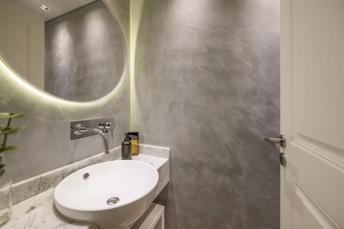 Baño moderno con lavabo ovalado blanco y espejo redondo retroiluminado — proyecto Segui, por Estudio Basa, en CABA