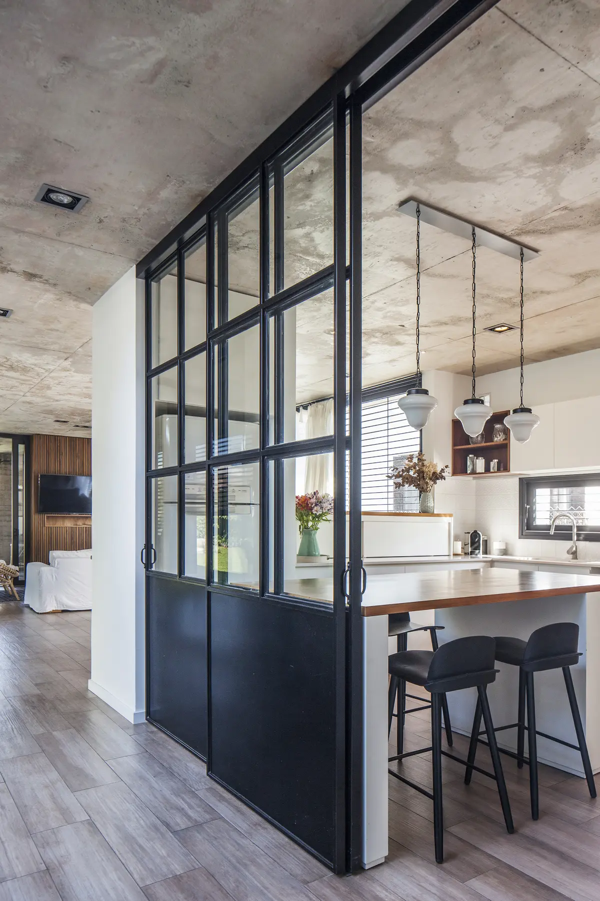 Cozinha moderna com ilha, divisória de vidro e concreto aparente — projeto Vivienda MI61, por Eg Arquitectura