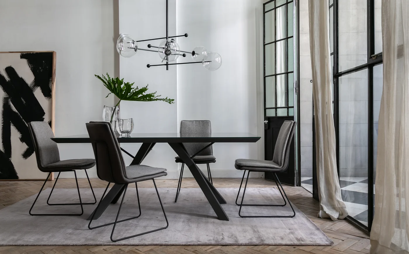 Comedor moderno con mesa negra, sillas grises y ventanal minimalista.