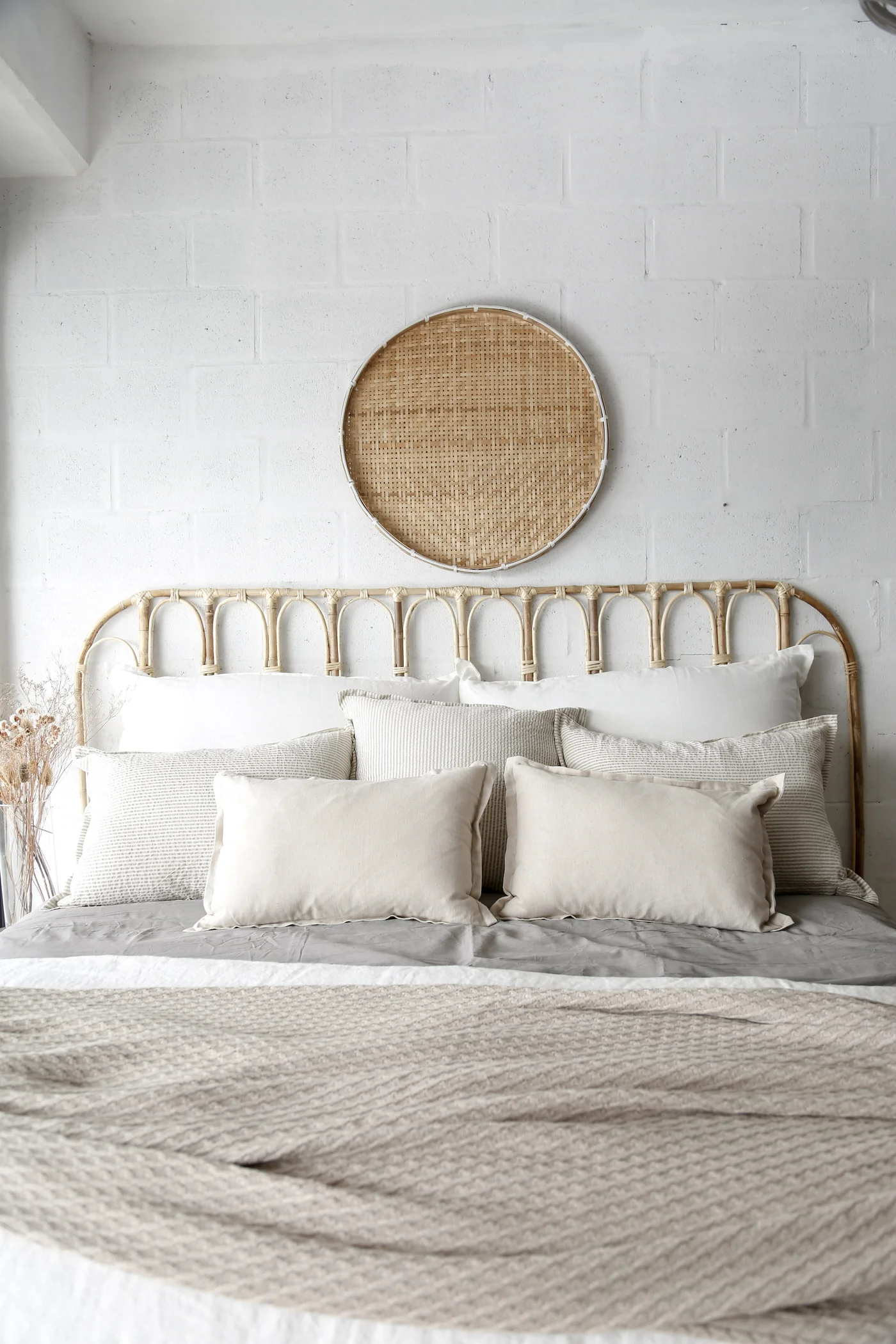 Dormitorio bohemio con cabecero de ratán y arte de pared tejido.