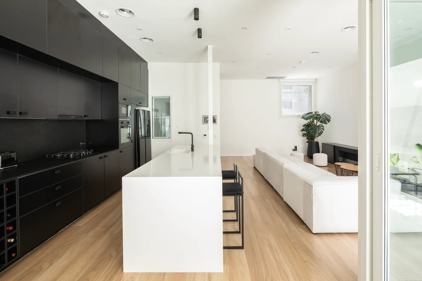 Cocina y sala de estar modernas, isla blanca grande, gabinetes negros.