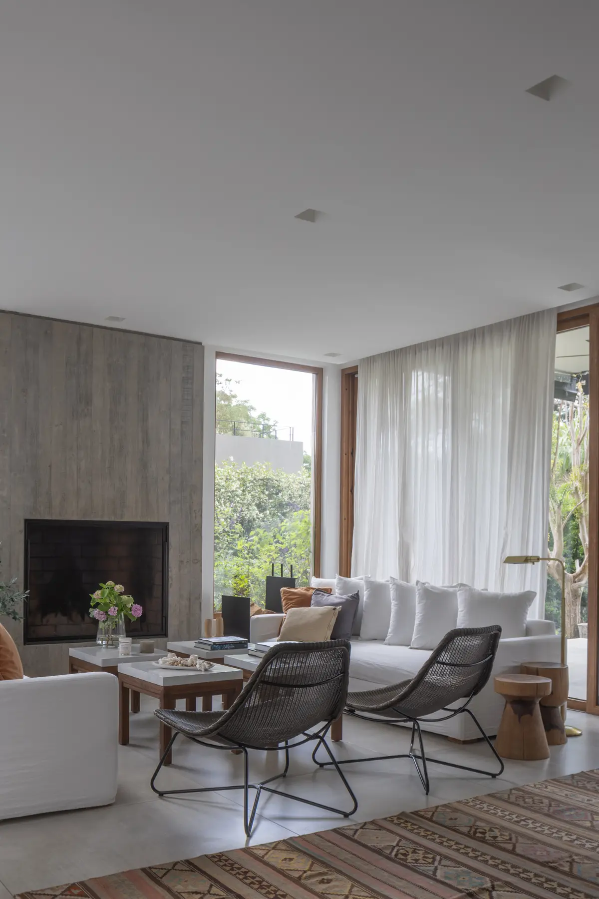 Living moderno con chimenea de hormigón y sillones de rattan — proyecto CASA OrAz, por Alfredo Orfila arquitectura, en San Isidro