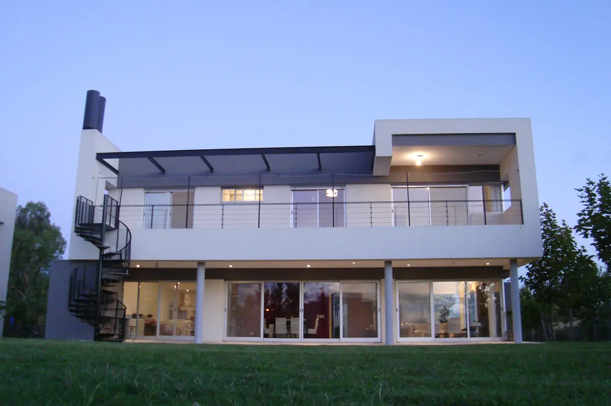 Fachada moderna com escada em espiral e grandes janelas — projeto Casa Laguna - Barrio Laguna del Sol (Tigre, Buenos Aires) German Salas arquitect, por German Salas arquitectura - 