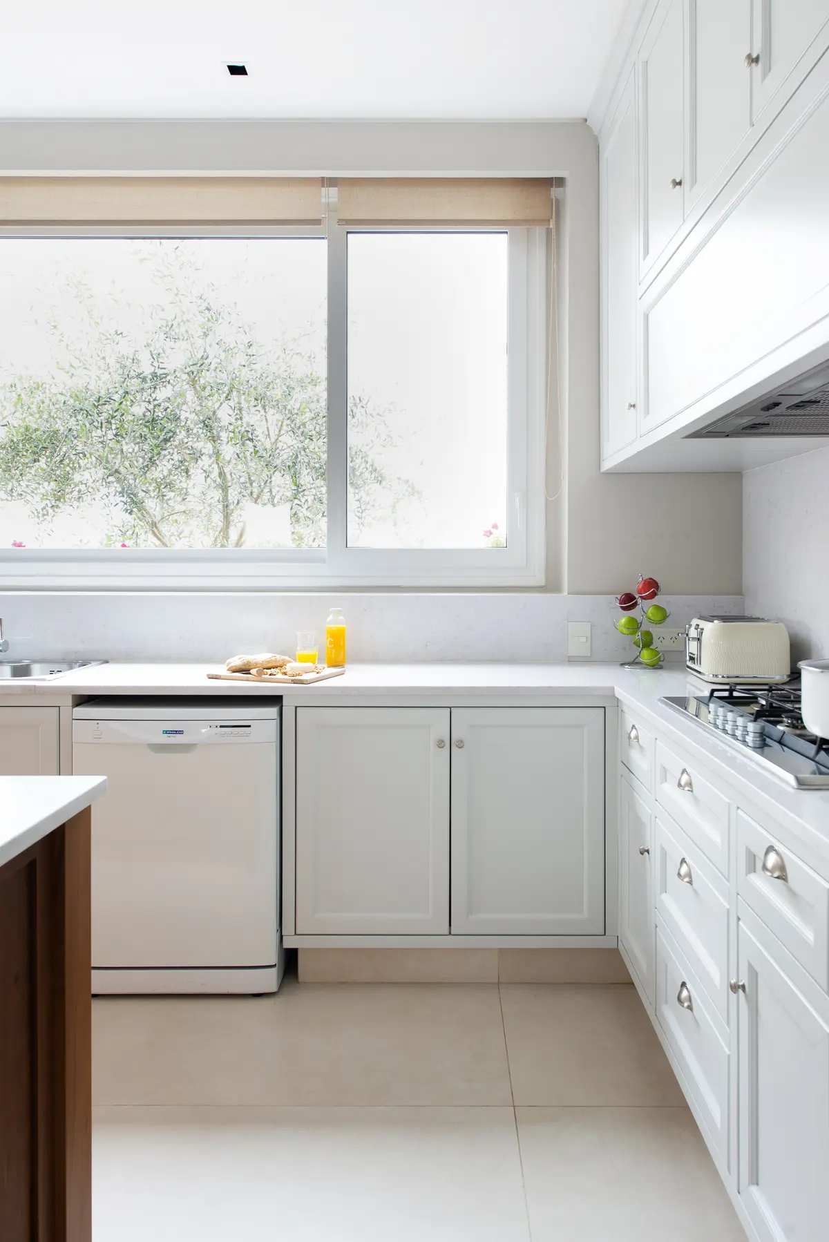 Cozinha moderna branca com janela grande e eletrodomésticos integrados — projeto Casa MF, por Estudio Junor, em Belén de Escobar
