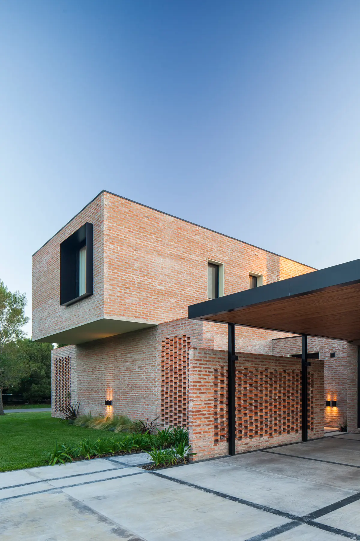 Fachada moderna de ladrillo visto con muros calados y pérgola — proyecto Casa Brick, por LSA. , en Pilar