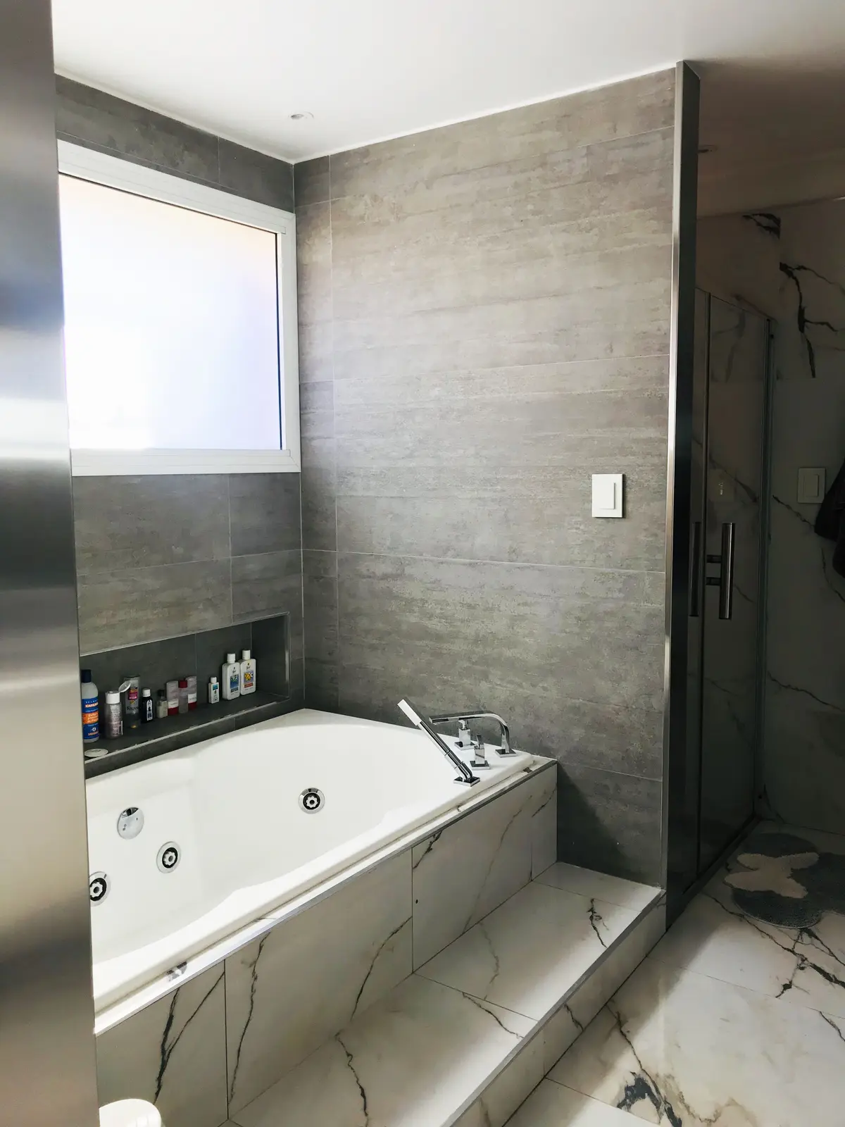 Baño moderno con bañera de hidromasaje y azulejos grises — proyecto Monroe - La Horqueta, por Mgc.arq, en La Horqueta