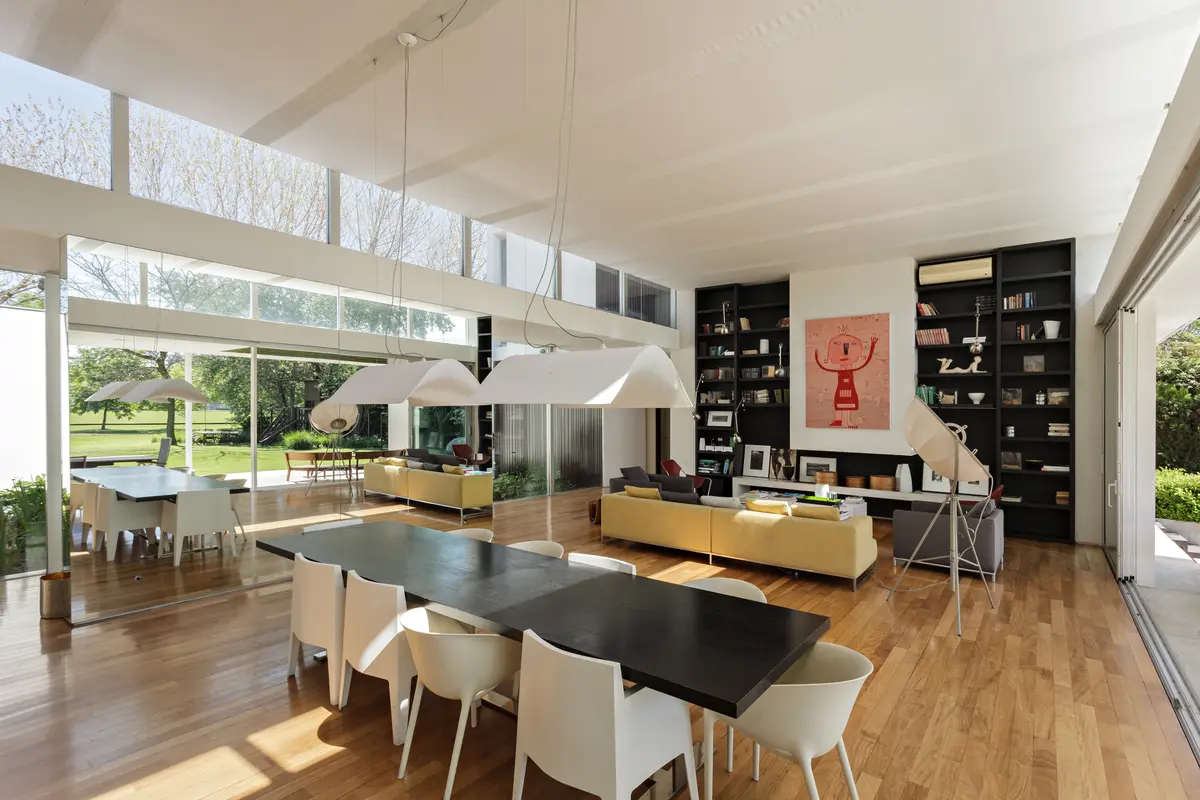 Sala de estar e jantar moderna com janelas amplas e piso de madeira — projeto Casa BD, por Alric Galindez Arquitectos