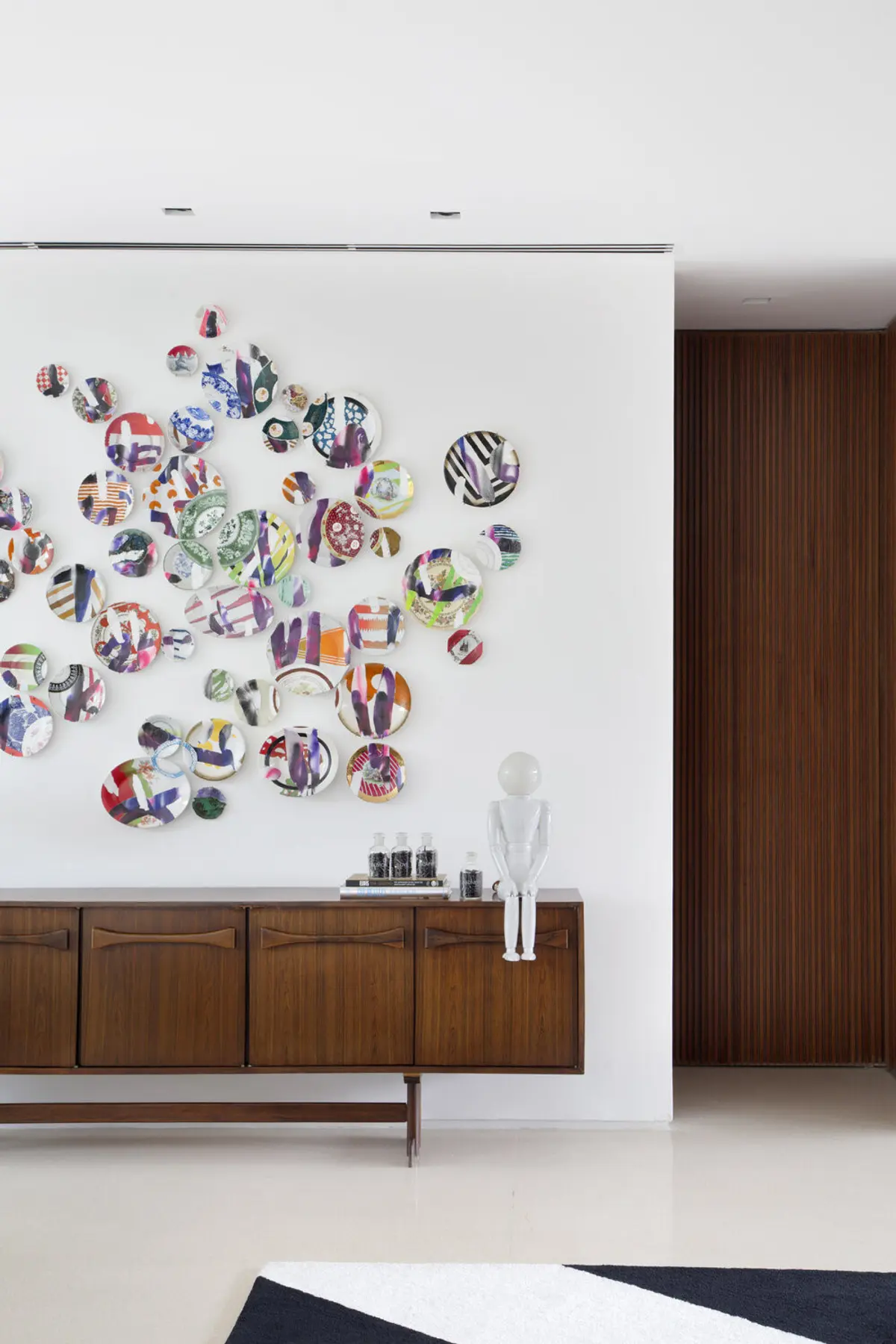 Living moderno con pared blanca, instalación artística circular y mueble de madera — proyecto BM House, por Studio Ro-ca