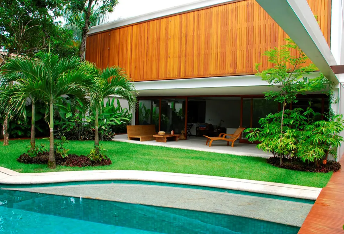 Casa moderna con pileta, deck y jardin frondoso con palmeras — proyecto Residência MI, por Gil Fialho