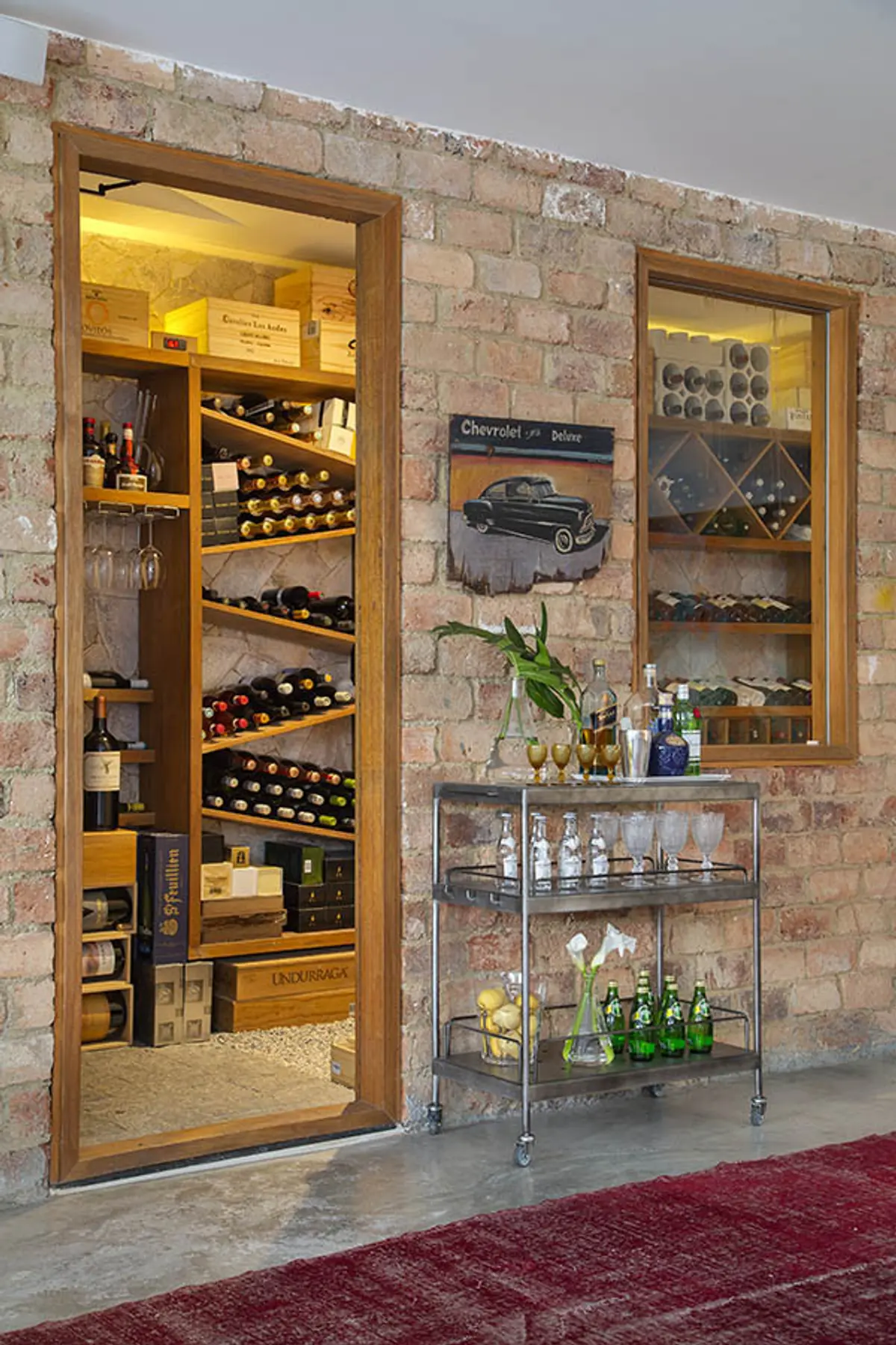 Local comercial de vinos con ladrillo visto y vitrinas iluminadas — proyecto Casa Jardim Guanabara, por Amanda Miranda