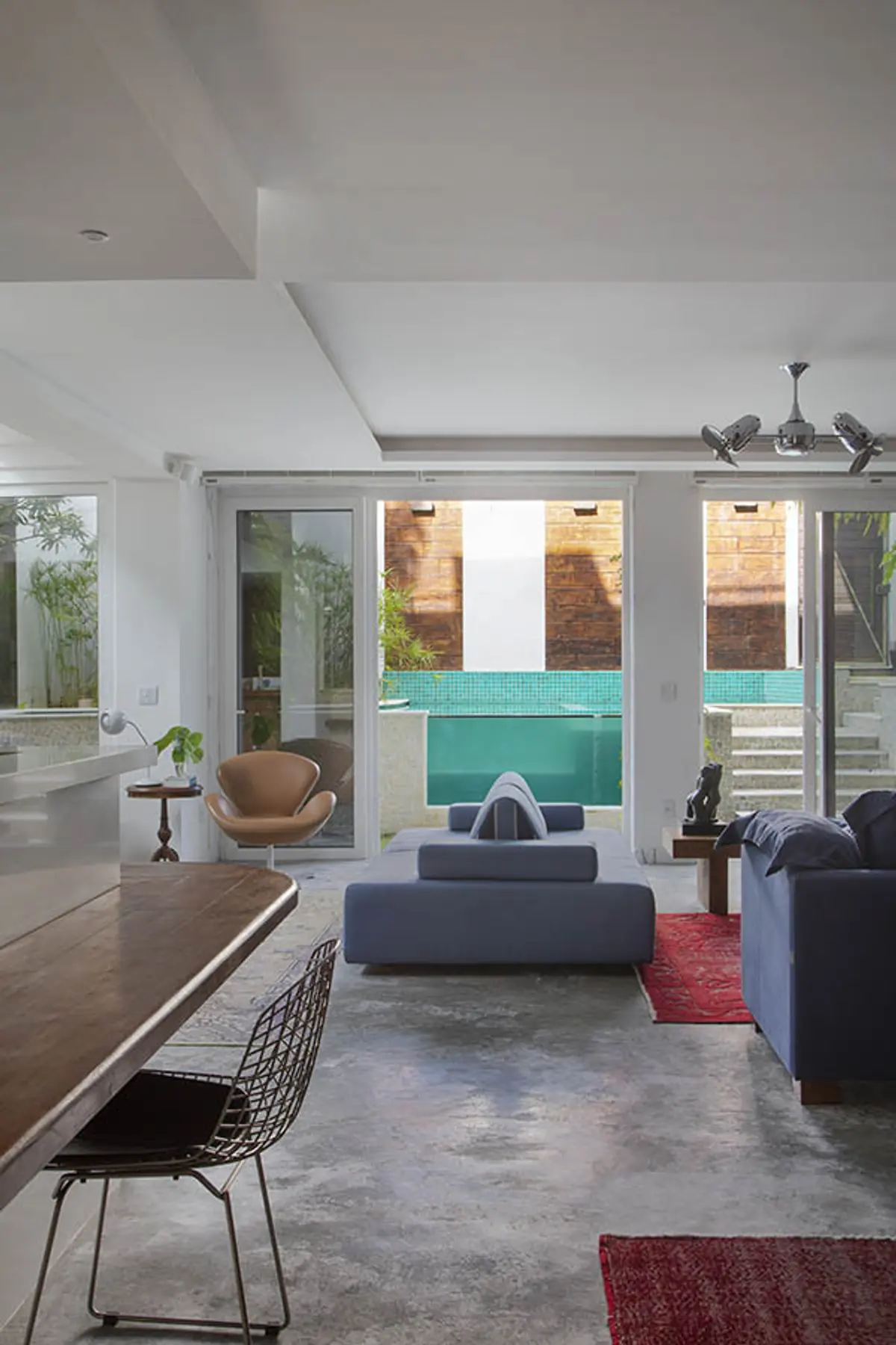 Living moderno con pileta turquesa y ventanales amplios hacia patio — proyecto Casa Jardim Guanabara, por Amanda Miranda