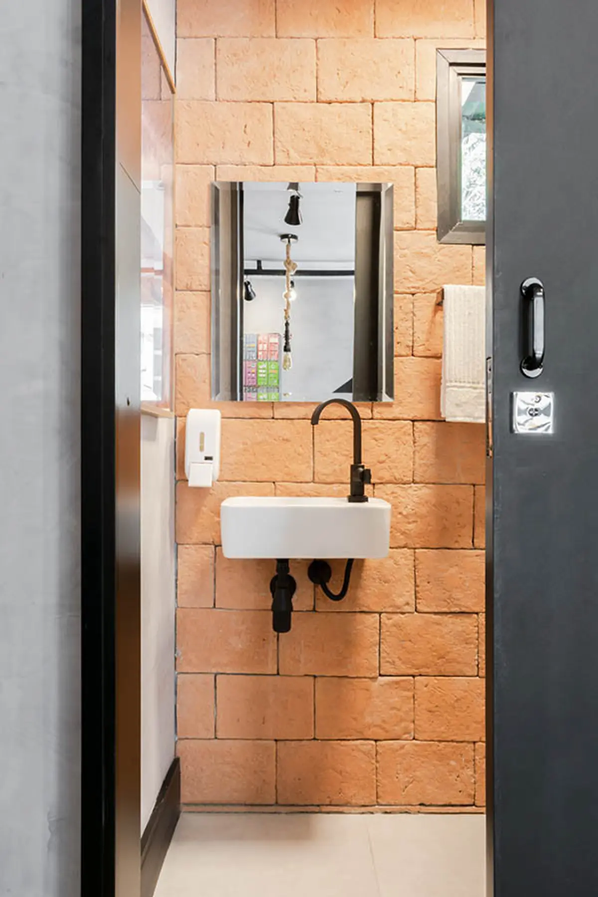 Toilette minimalista con pared de ladrillo visto y espejo industrial — proyecto Escritório Itaipu, por Amanda Miranda