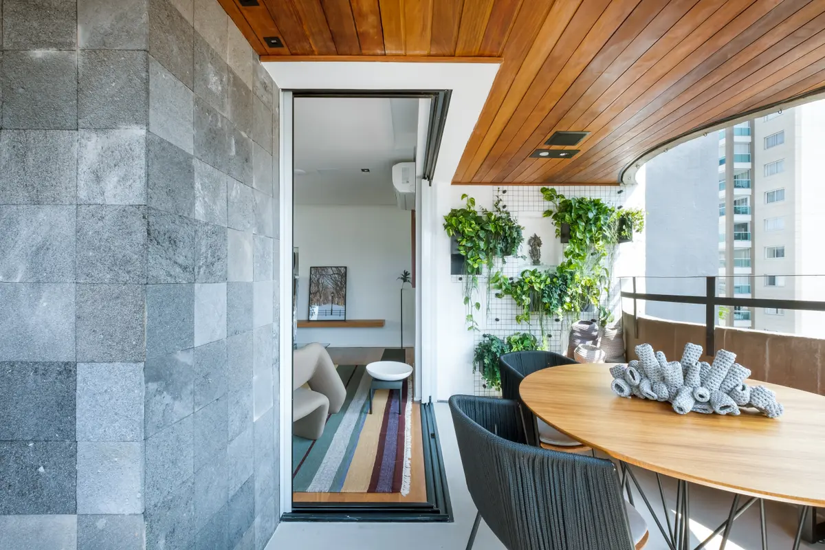 Balcón moderno con pared verde, piedra y madera — proyecto APTO RF, por Zalc Arquitetura 