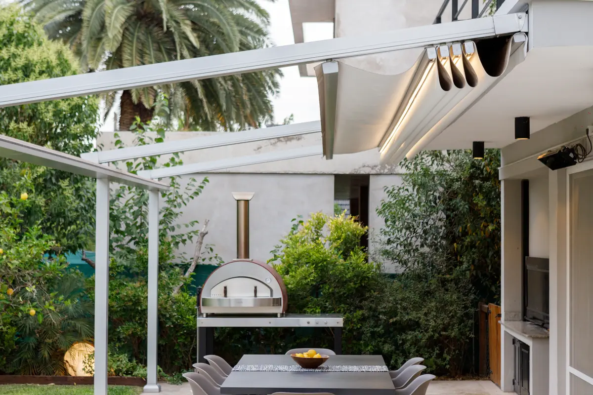 Área gourmet moderna com forno de pizza e pergolado retrátil — projeto TOLDER - PERGOLAS, por Argentina en Obra 2024, em Rincón de Milberg