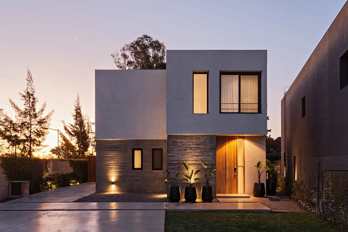 Fachada moderna de casa de dos plantas con volúmenes geométricos y luces cálidas — proyecto CASA RDV, por Rastro Estudio, en San Isidro