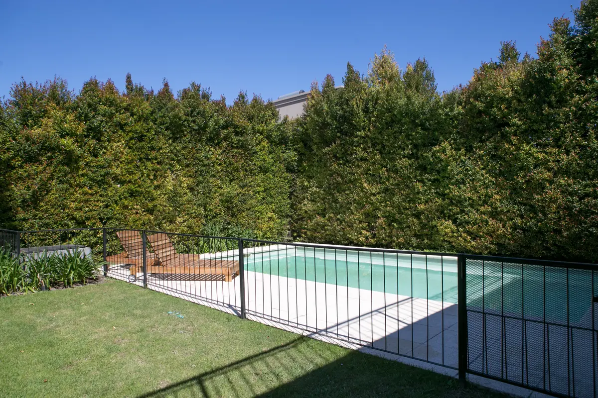 Pileta con deck y cerco de madera en jardín con árboles — proyecto Ayres Plaza, por ATO Arquitectos, en Ayres Plaza