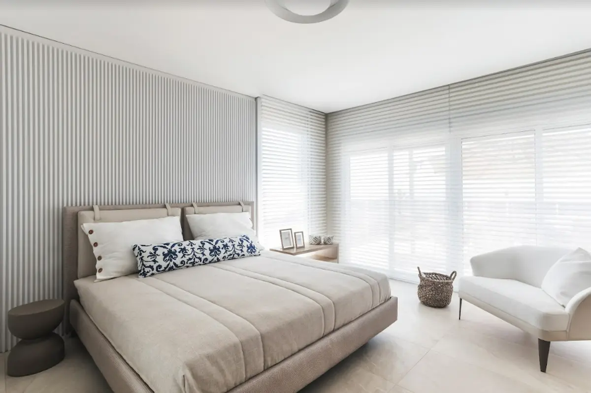 Quarto minimalista com parede de ripas e poltrona branca — projeto Projeto Destaque Archclub, por ARQUITETARE POR ELAINE ZANON & CLAUDIA MACHADO