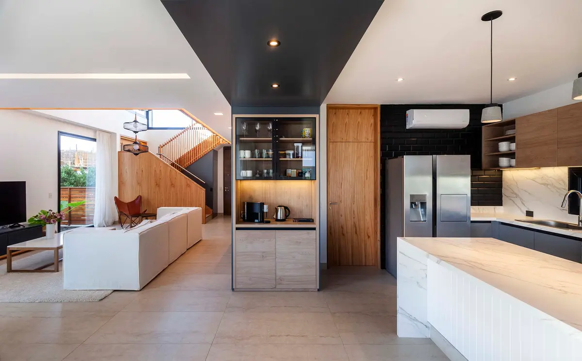 Sala de estar e cozinha moderna em plano aberto com ilha e janelas do chão ao teto — projeto Castaños, por GO arquitectos, em Rincón de Milberg